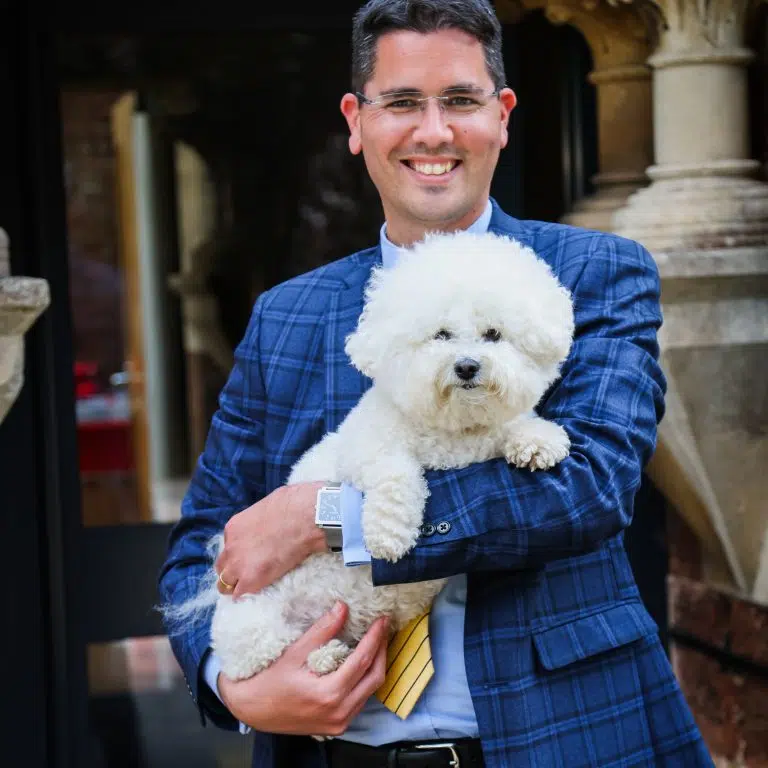 Man in blue suit holding a white dog