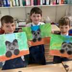 students holding paintings of a panda