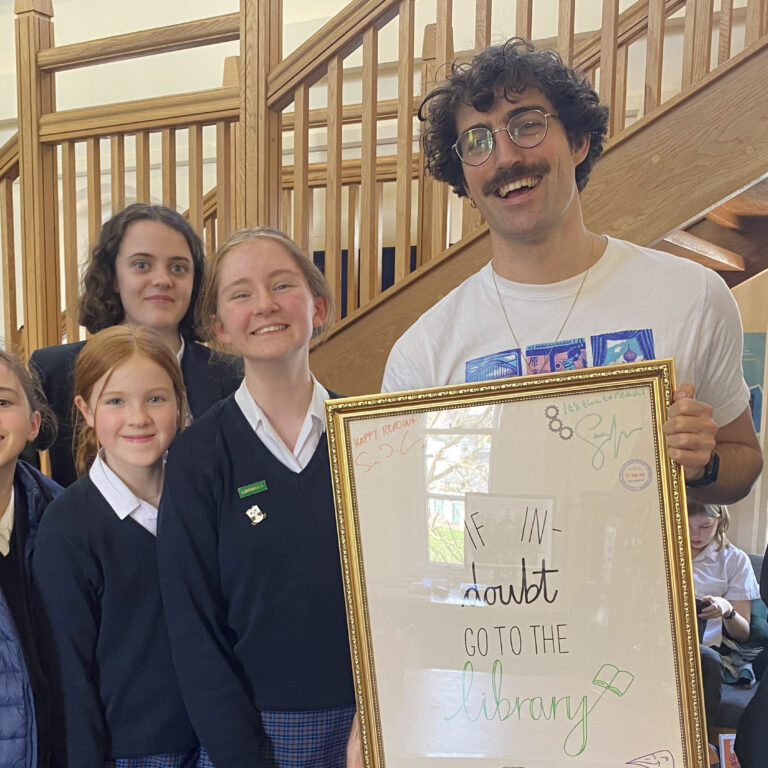 students and teacher holding a handmade sign for a library