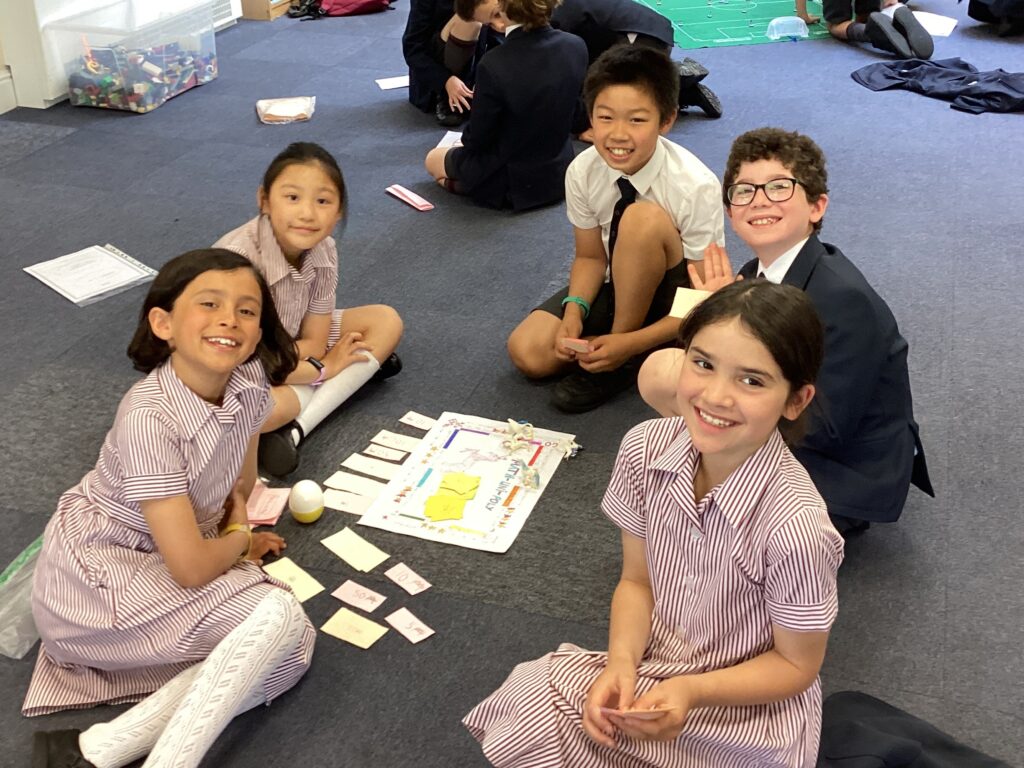 a group of young students sitting on the carpet around a piece of schoolwork