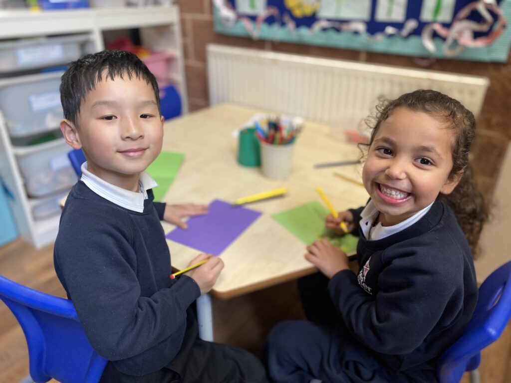 two pre-prep children writing on coloured card