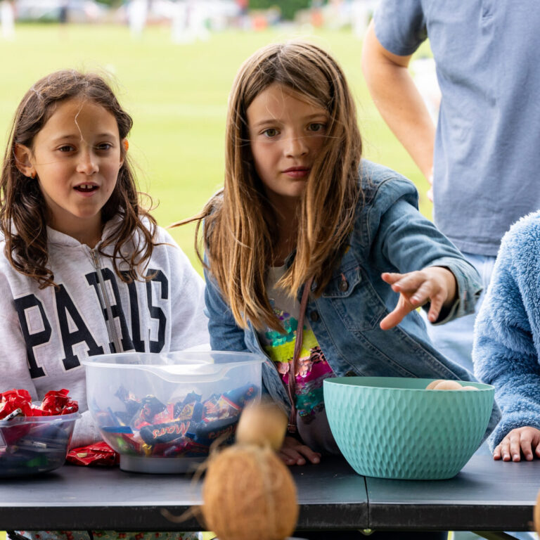 three girls standing at a table with bowls of chocolates