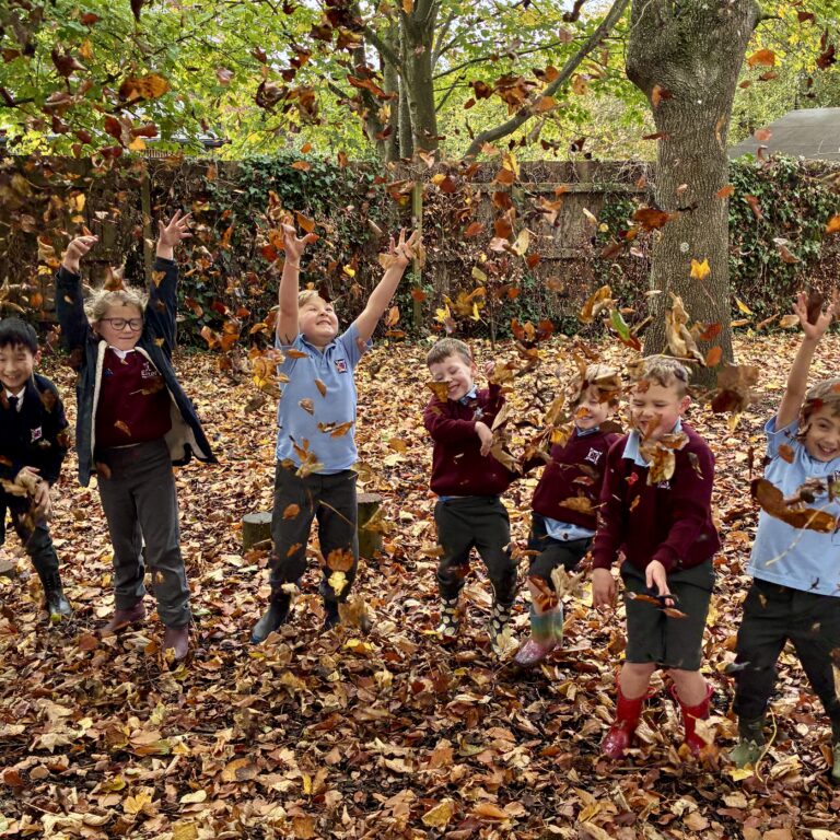 Smiling pupils throwing autumn leaves in the air