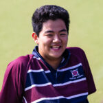 Happy smiling boy relaxing on hockey astro in Exeter School sports uniform