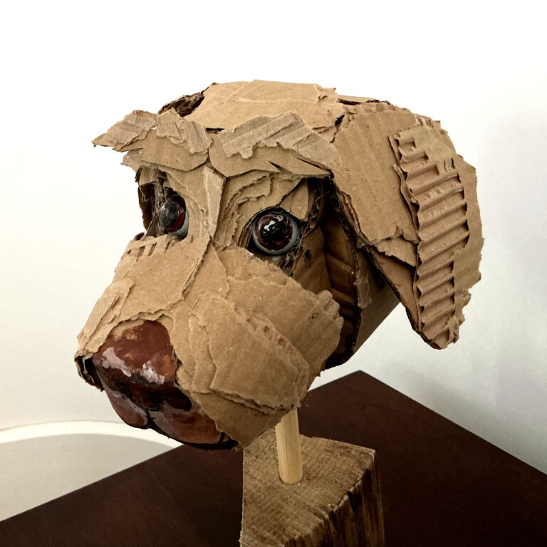 Close-up of a cardboard sculpture head made from torn corrugated cardboard with two large googly eyes.