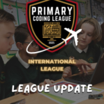 Three primary school pupils collaborating on a laptop at a classroom desk, overlaid with text reading "Primary Coding League – International League – League Update".