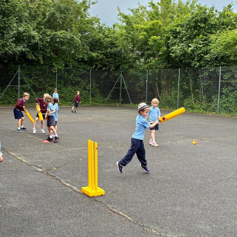 Children playing cricket on hard playground