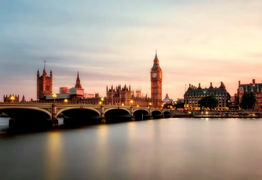 London skyline at dusk with Big Ben and the Houses of Parliament along the River Thames and Westminster Bridge in the foreground.