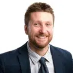 Suited bearded man smiling with white background