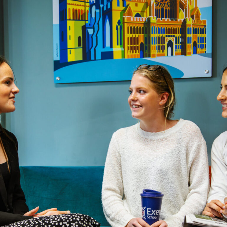 3 young woman sat on an orange and blue sofa