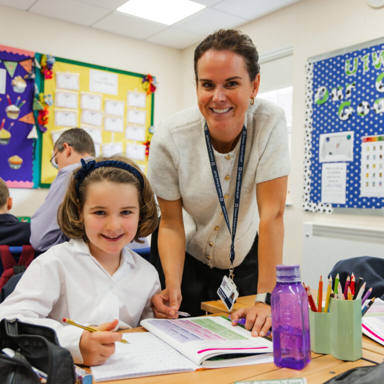 teacher and pupil smiling whilst doing work