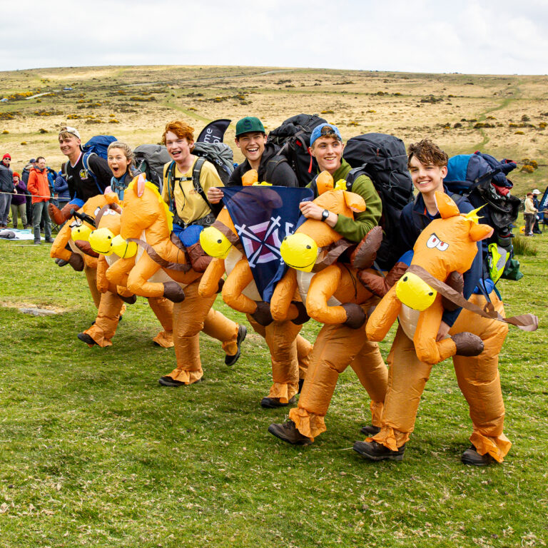 5 people dressed up with inflatables crossing the finish line.