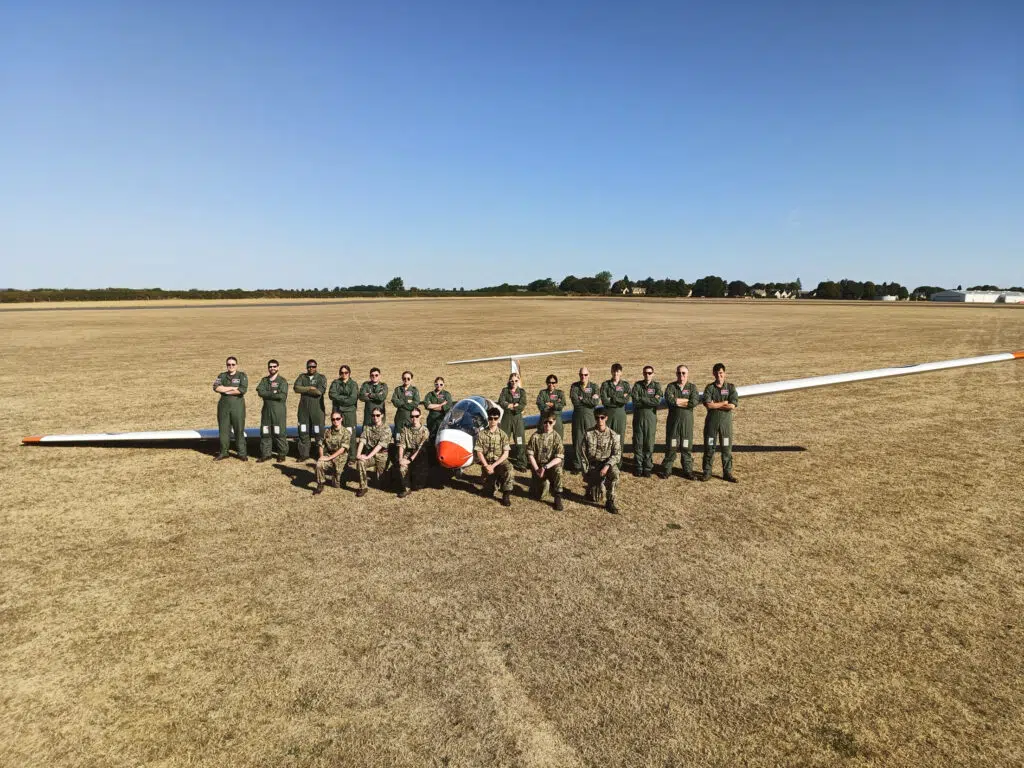 a group of men on an airspace field in cadet uniforms in front of a plane