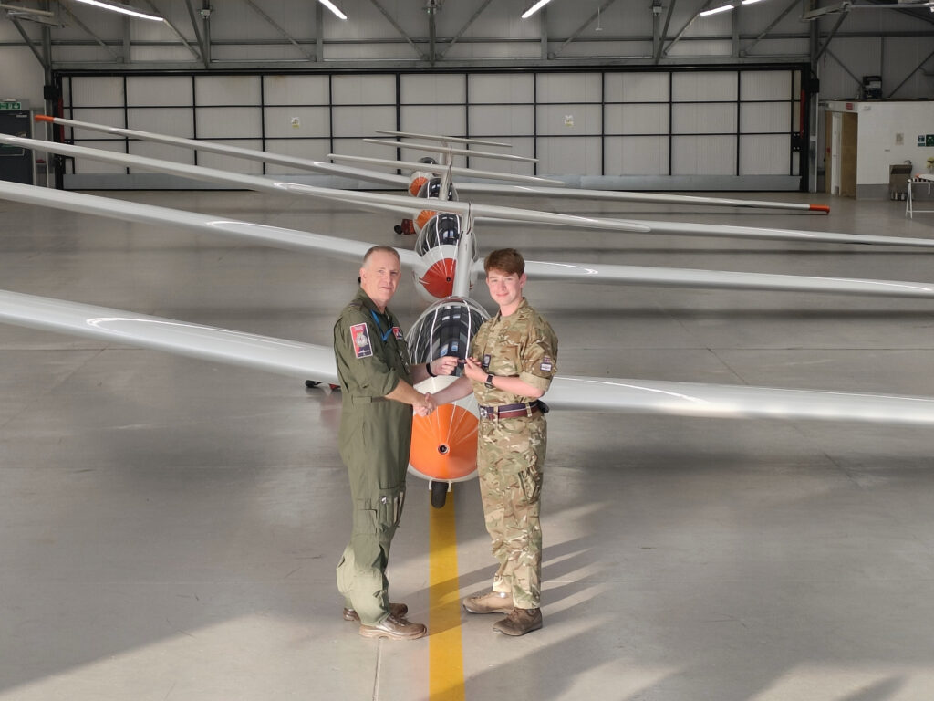 men in cadet uniform in front of a plane in a hall