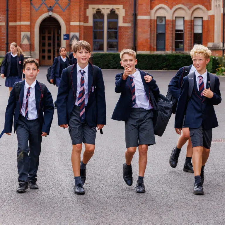 4 boys in school uniform walking in front of red brick school building